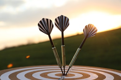 Photo of Targeting. Dart board with arrows outdoors, closeup