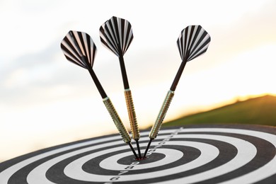 Photo of Targeting. Dart board with arrows outdoors, closeup