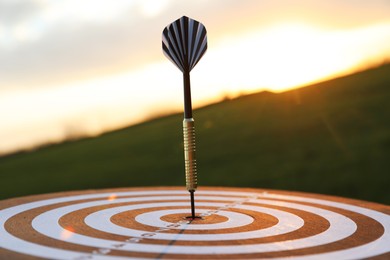 Photo of Targeting. Dart board with arrow outdoors, closeup
