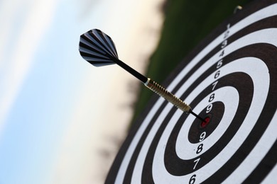 Photo of Targeting. Dart board with arrow outdoors, closeup