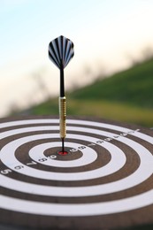 Photo of Targeting. Dart board with arrow outdoors, closeup