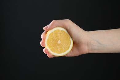 Photo of Woman with lemon on black background, closeup