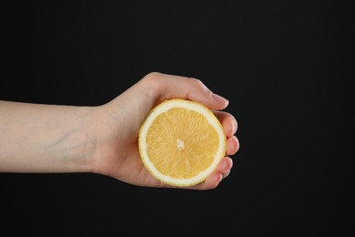 Photo of Woman with lemon on black background, closeup