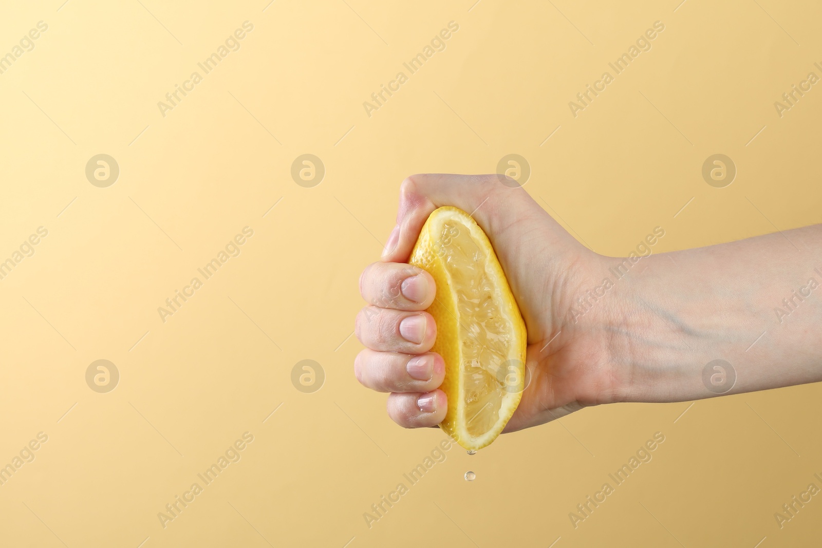 Woman squeezing lemon on yellow background, closeup. Space for text Photo of Woman squeezing lemon on yellow background, closeup. Space for text