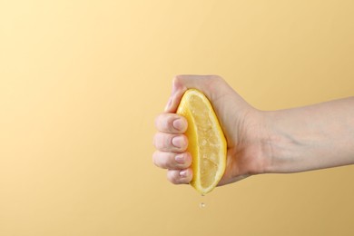Photo of Woman squeezing lemon on yellow background, closeup. Space for text