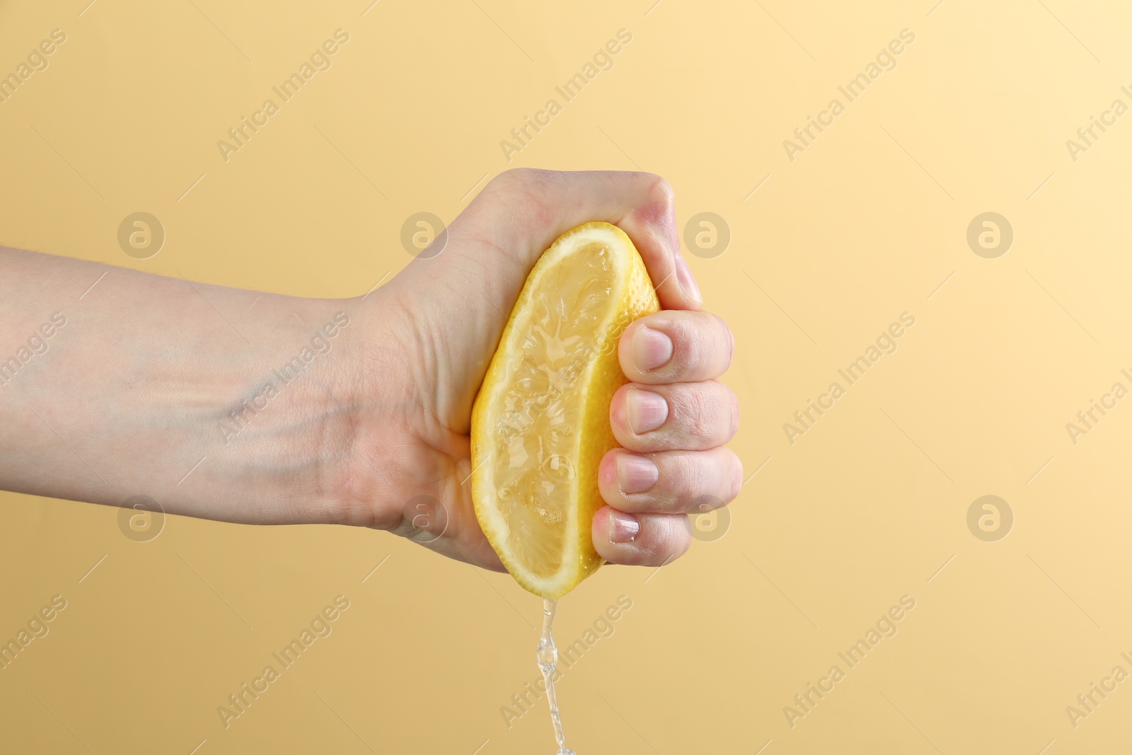 Woman squeezing lemon on yellow background, closeup Photo of Woman squeezing lemon on yellow background, closeup