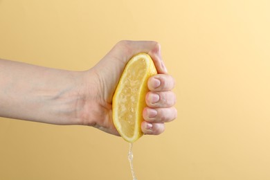 Photo of Woman squeezing lemon on yellow background, closeup