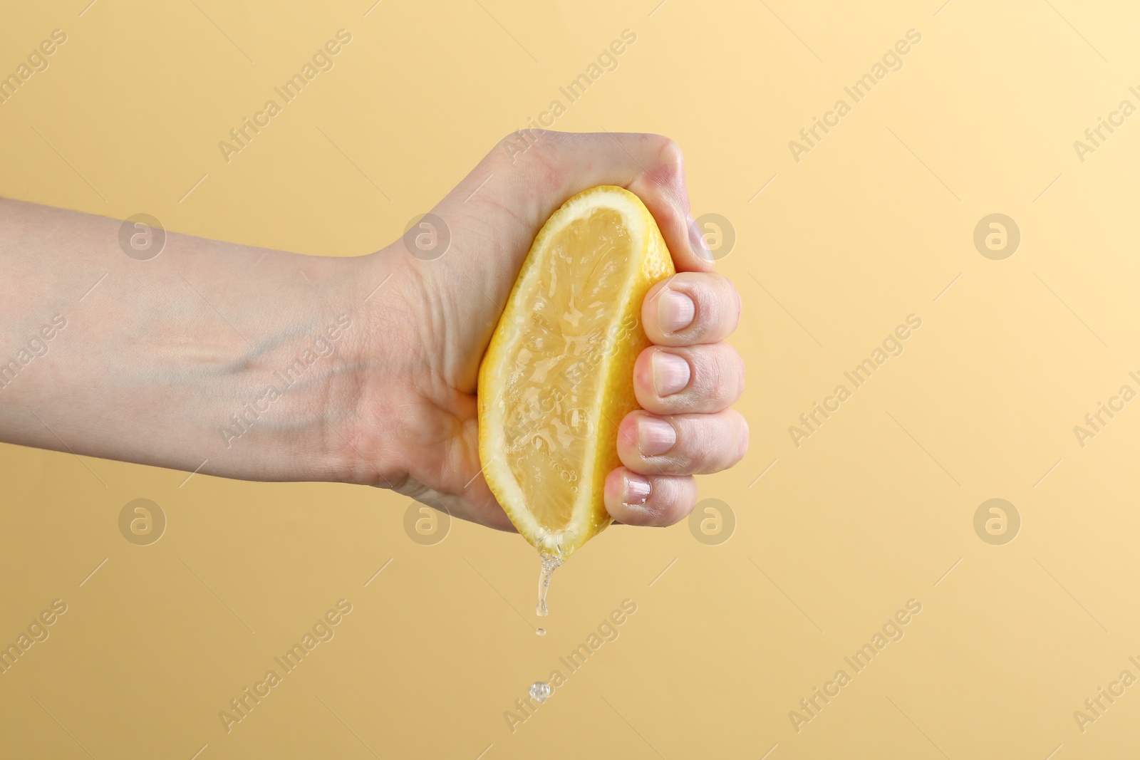 Woman squeezing lemon on yellow background, closeup Photo of Woman squeezing lemon on yellow background, closeup