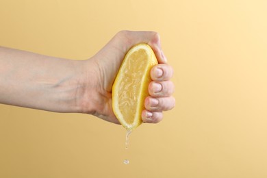 Photo of Woman squeezing lemon on yellow background, closeup