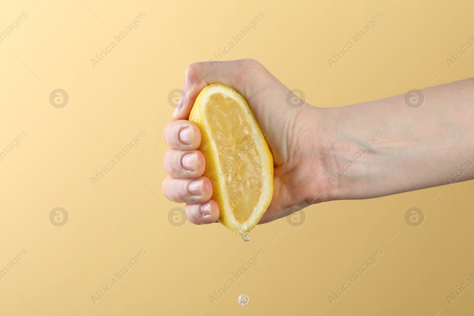 Woman squeezing lemon on yellow background, closeup Photo of Woman squeezing lemon on yellow background, closeup