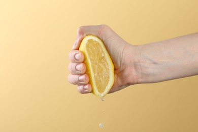 Photo of Woman squeezing lemon on yellow background, closeup