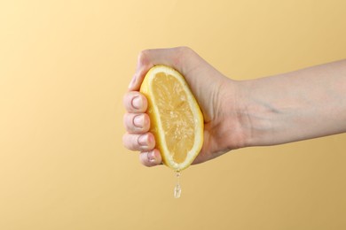 Photo of Woman squeezing lemon on yellow background, closeup