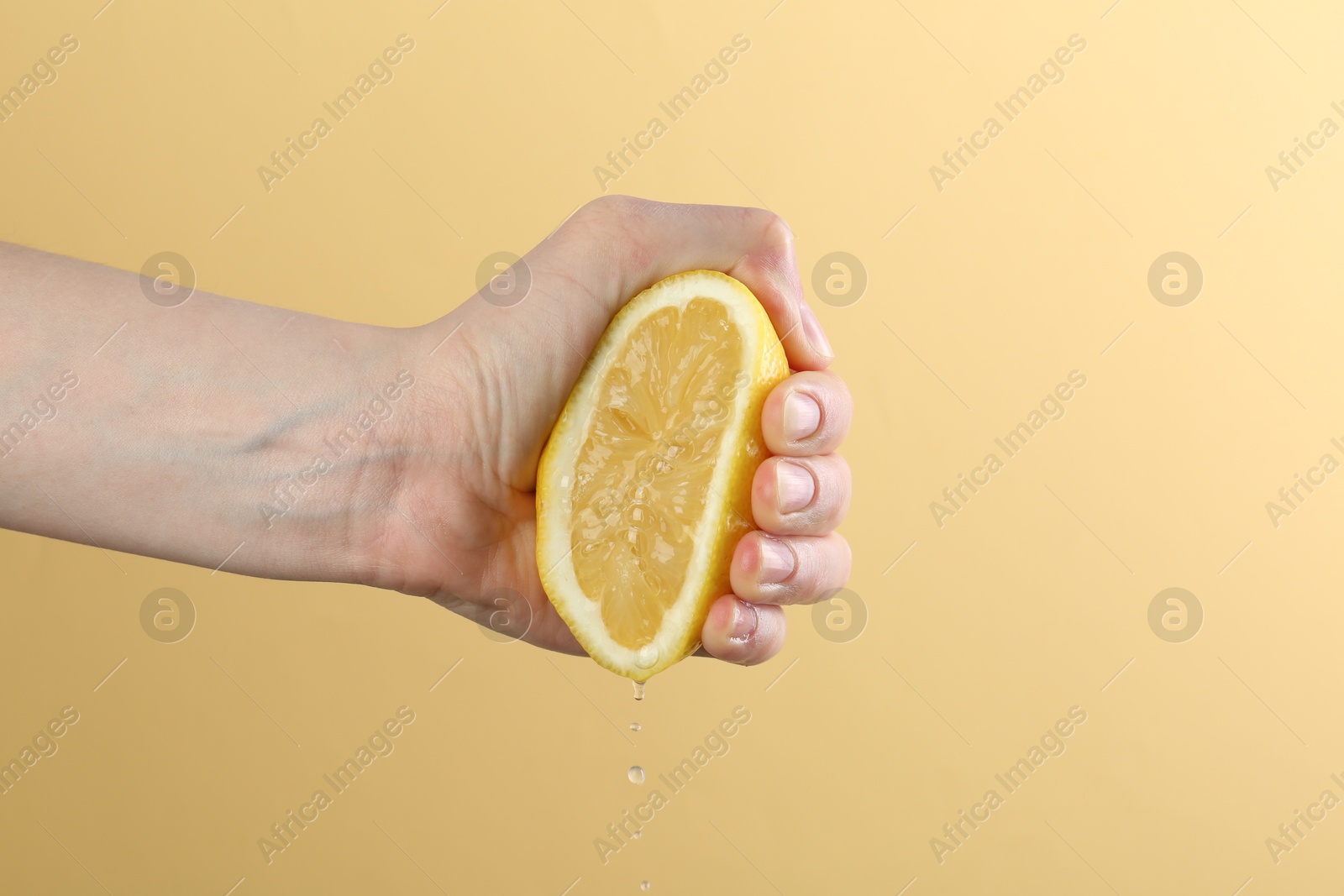 Woman squeezing lemon on yellow background, closeup Photo of Woman squeezing lemon on yellow background, closeup