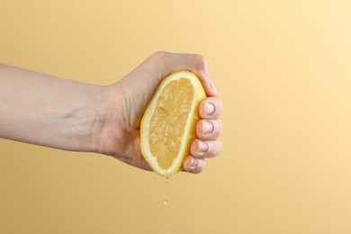 Photo of Woman squeezing lemon on yellow background, closeup
