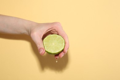 Photo of Woman squeezing lime on yellow background, closeup. Space for text