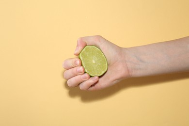 Photo of Woman squeezing lime on yellow background, closeup