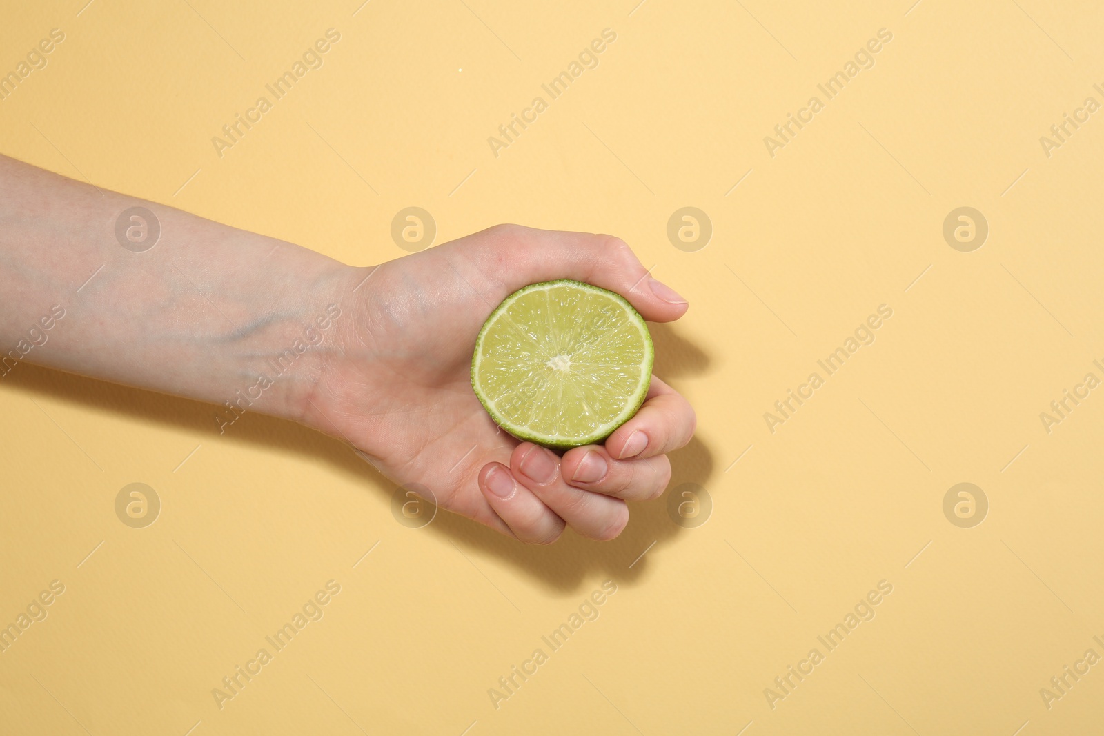 Woman with lime on yellow background, closeup Photo of Woman with lime on yellow background, closeup