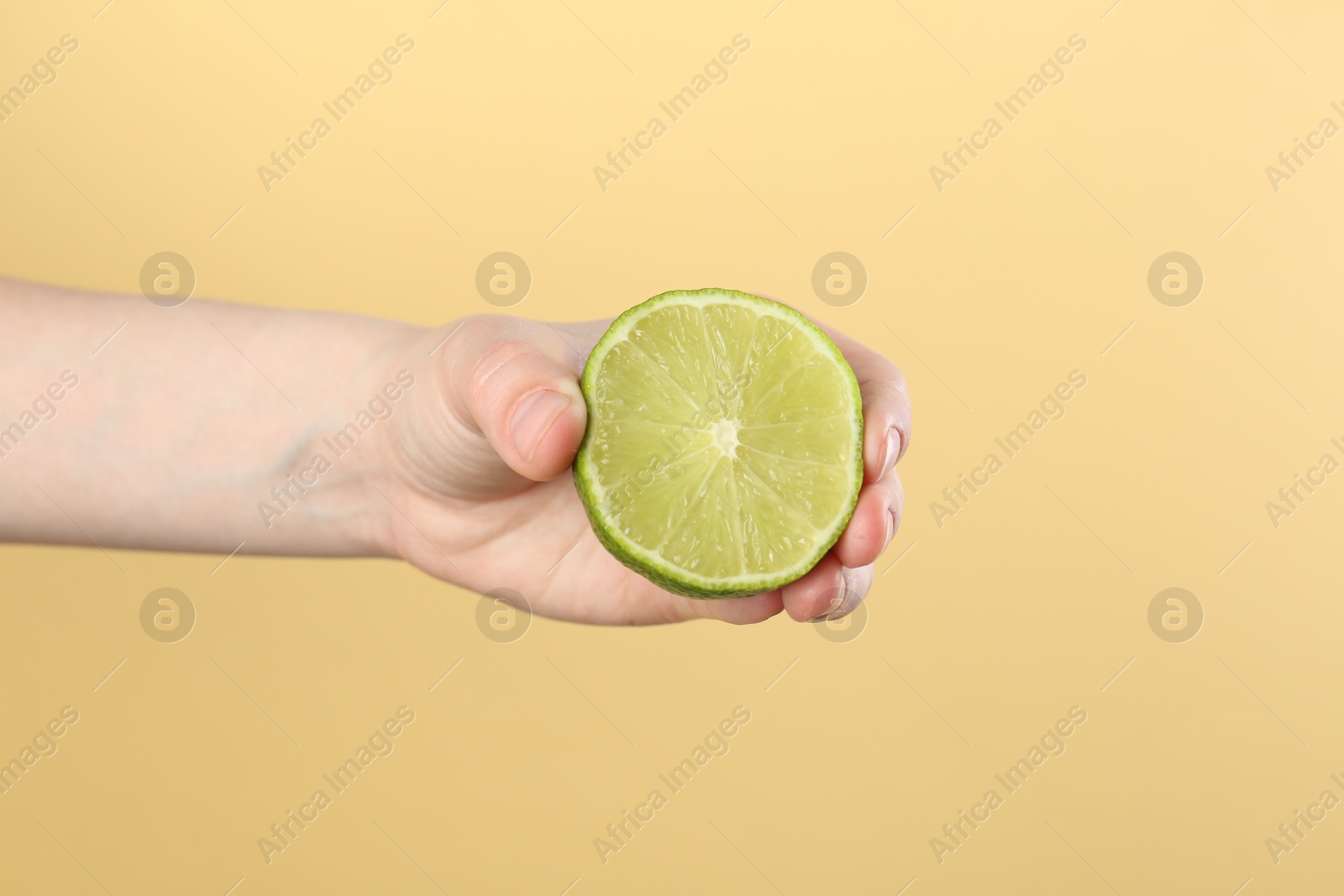 Woman squeezing lime on yellow background, closeup Photo of Woman squeezing lime on yellow background, closeup