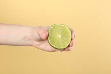 Photo of Woman squeezing lime on yellow background, closeup