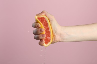 Photo of Woman squeezing grapefruit on pink background, closeup