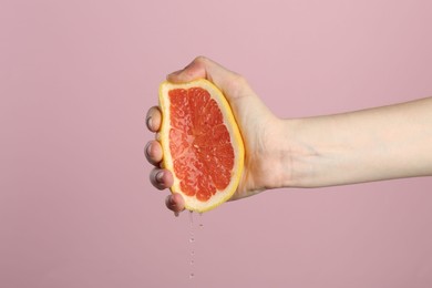 Photo of Woman squeezing grapefruit on pink background, closeup