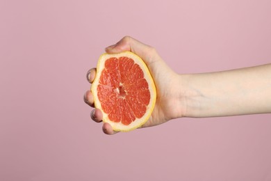 Photo of Woman squeezing grapefruit on pink background, closeup