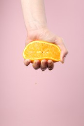 Photo of Woman squeezing orange on pink background, closeup. Space for text
