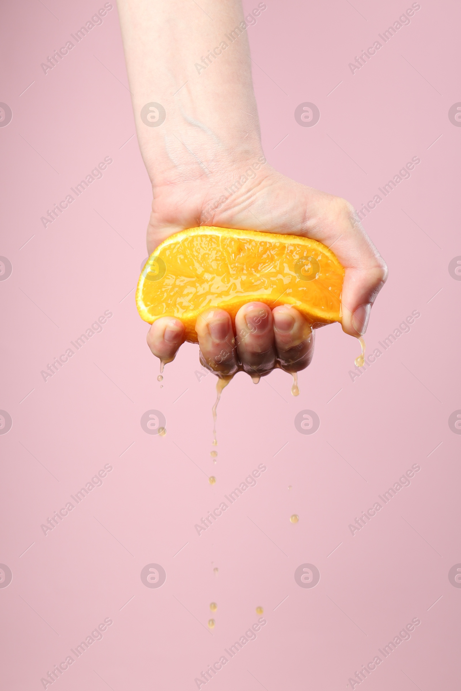 Woman squeezing orange on pink background, closeup. Space for text Photo of Woman squeezing orange on pink background, closeup. Space for text