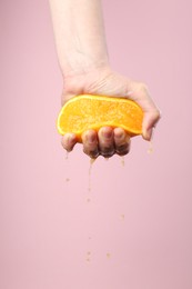 Photo of Woman squeezing orange on pink background, closeup. Space for text