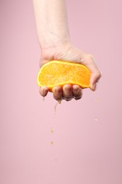 Photo of Woman squeezing orange on pink background, closeup. Space for text