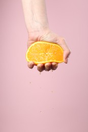 Photo of Woman squeezing orange on pink background, closeup. Space for text