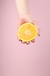 Photo of Woman with orange on pink background, closeup. Space for text