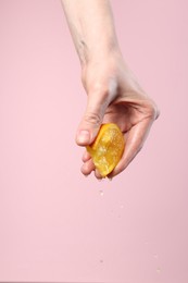 Photo of Woman squeezing orange on pink background, closeup. Space for text