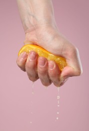 Photo of Woman squeezing orange on pink background, closeup