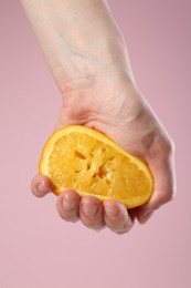 Photo of Woman squeezing orange on pink background, closeup