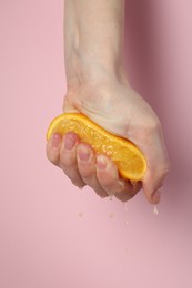 Photo of Woman squeezing orange on pink background, closeup