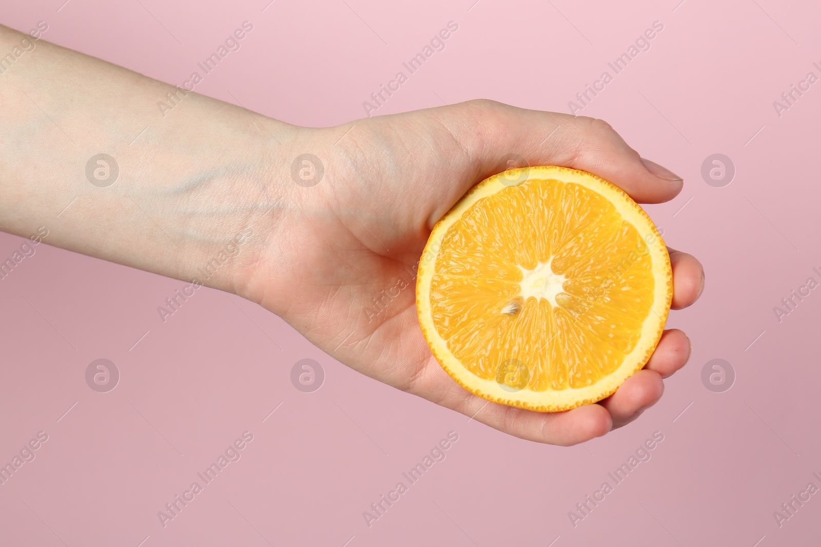 Woman with orange on pink background, closeup Photo of Woman with orange on pink background, closeup
