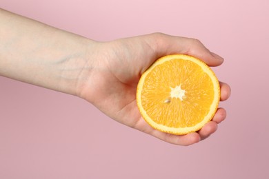 Photo of Woman with orange on pink background, closeup