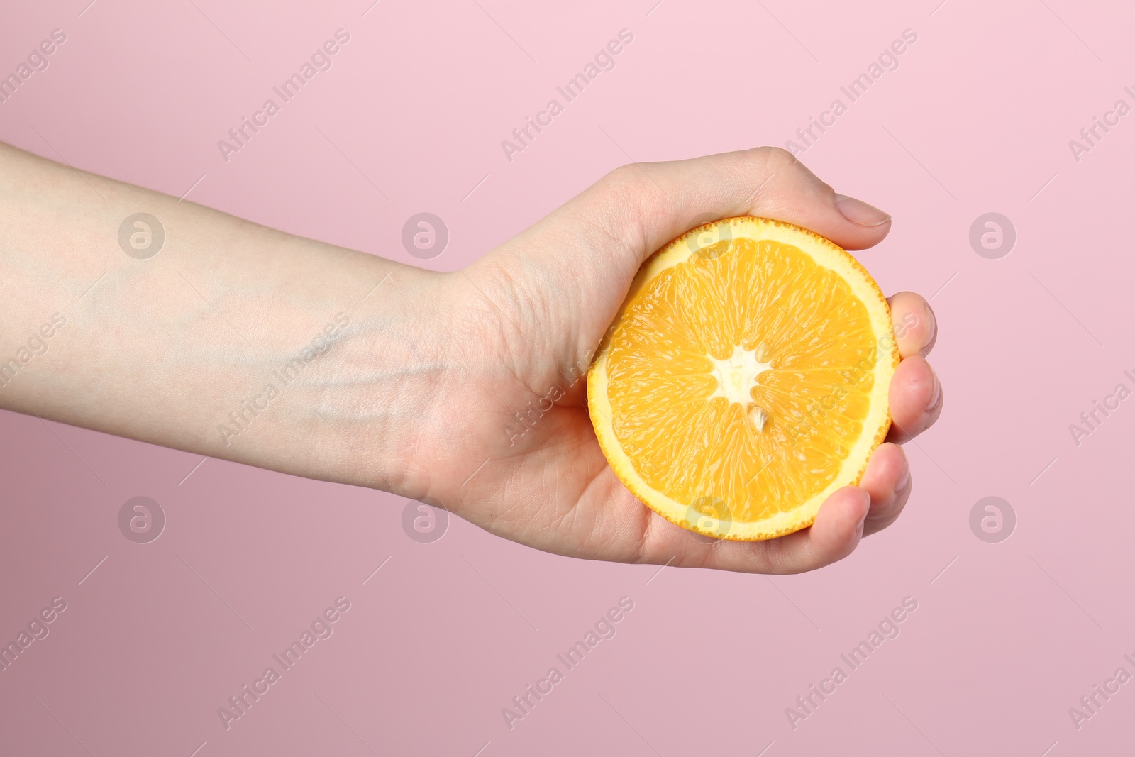 Woman with orange on pink background, closeup Photo of Woman with orange on pink background, closeup