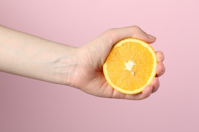 Photo of Woman with orange on pink background, closeup