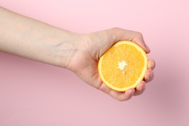 Photo of Woman with orange on pink background, closeup