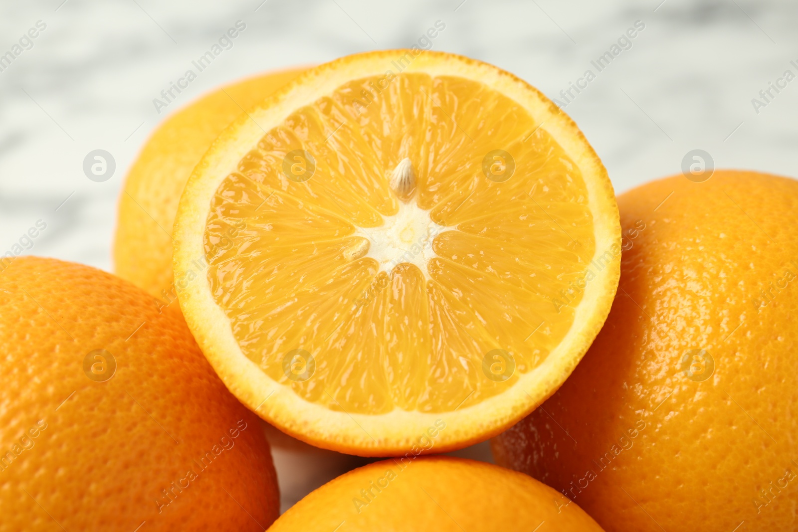 Half of fresh orange among whole ones on blurred light background, closeup Photo of Half of fresh orange among whole ones on blurred light background, closeup