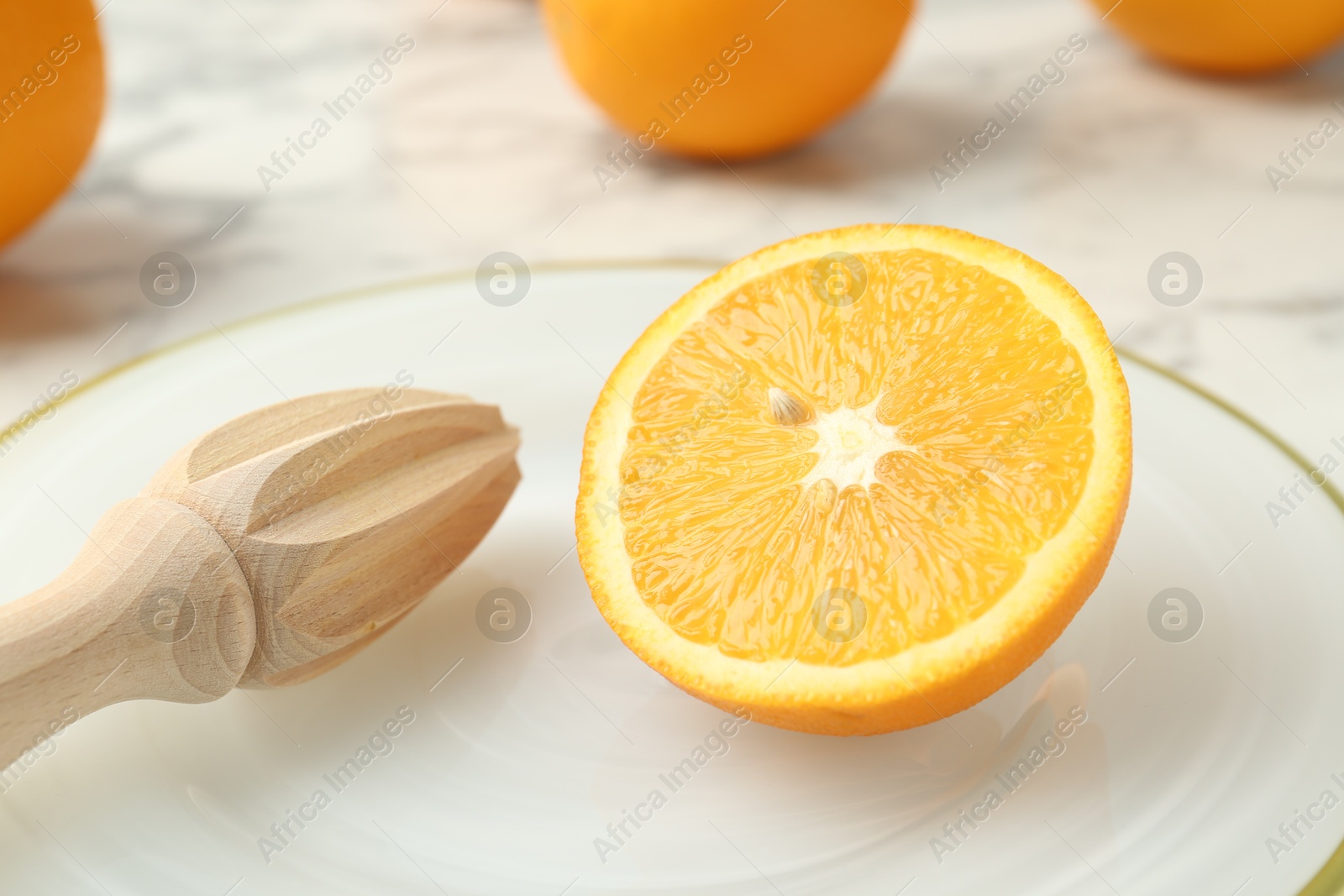 Half of fresh orange and squeezer on white marble table, closeup Photo of Half of fresh orange and squeezer on white marble table, closeup