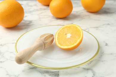 Photo of Half of fresh orange and squeezer on white marble table, closeup