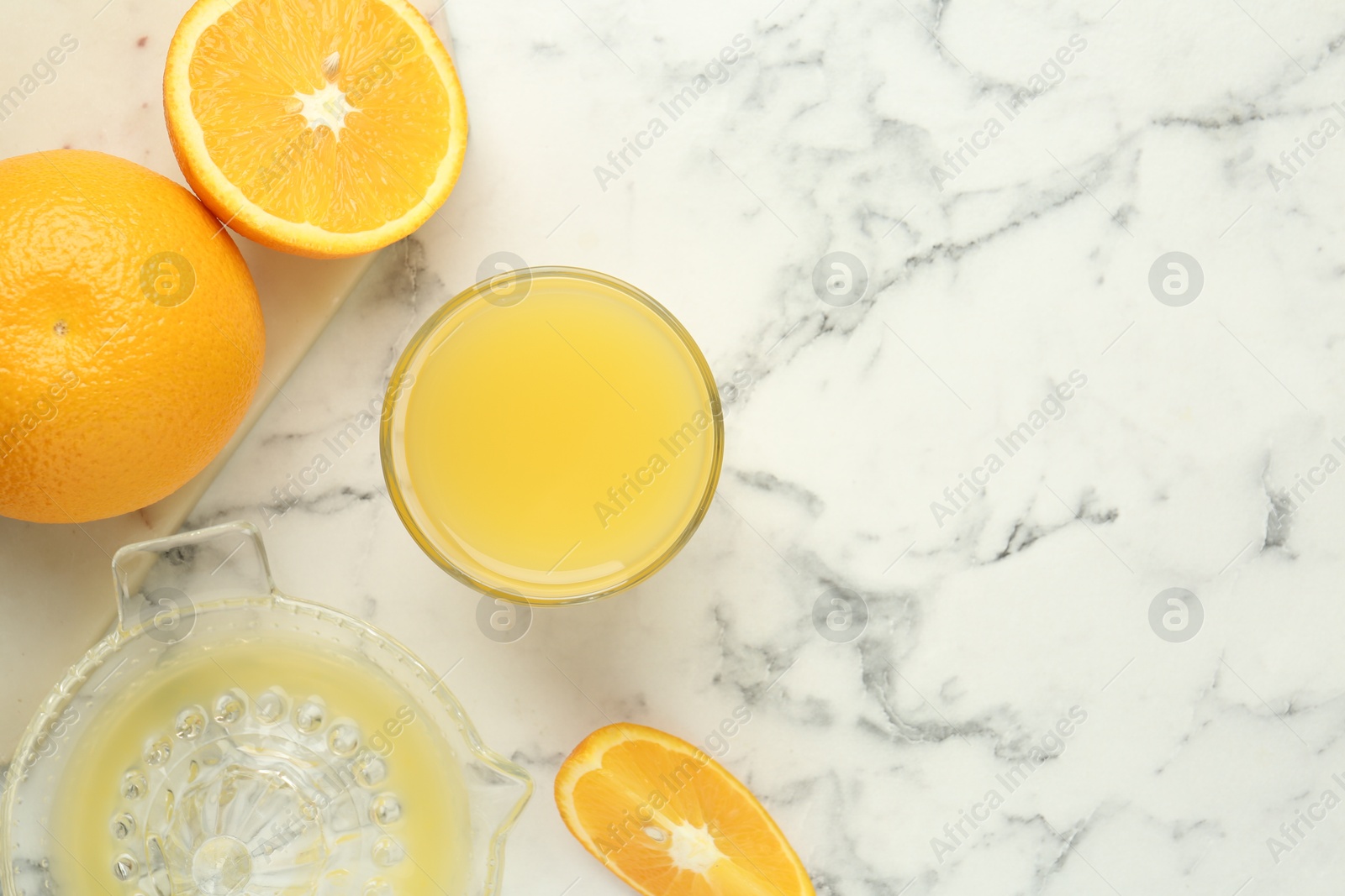 Fresh orange juice, fruits and squeezer on white marble table, flat lay. Space for text Photo of Fresh orange juice, fruits and squeezer on white marble table, flat lay. Space for text