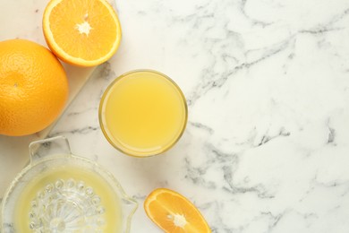 Photo of Fresh orange juice, fruits and squeezer on white marble table, flat lay. Space for text