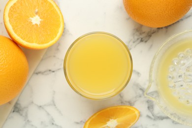 Photo of Fresh orange juice, fruits and squeezer on white marble table, flat lay