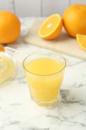 Photo of Fresh orange juice and fruits on white marble table, closeup