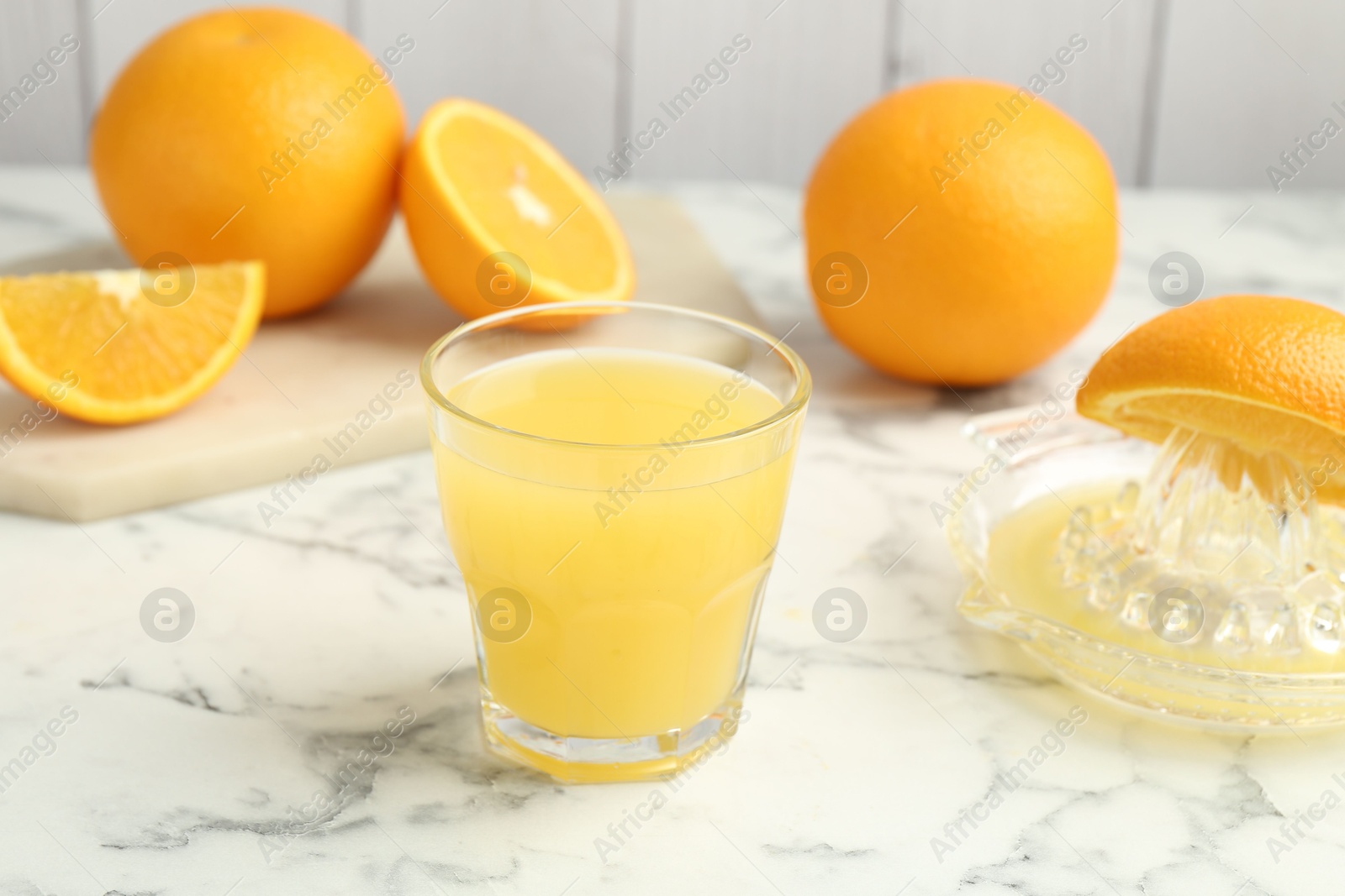 Fresh orange juice, fruits and squeezer on white marble table, closeup Photo of Fresh orange juice, fruits and squeezer on white marble table, closeup