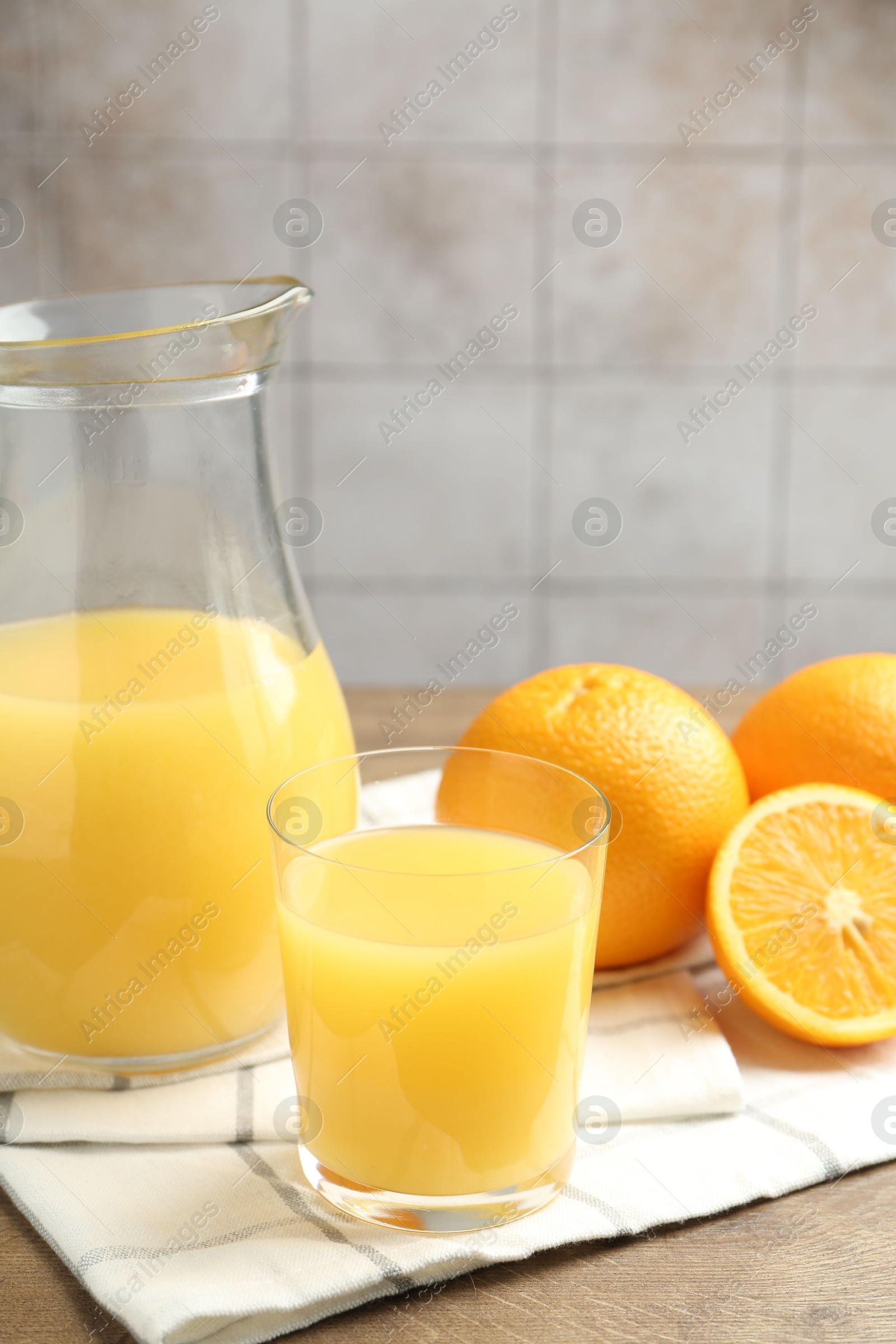 Fresh orange juice and fruits on wooden table against grey tiled wall, closeup Photo of Fresh orange juice and fruits on wooden table against grey tiled wall, closeup